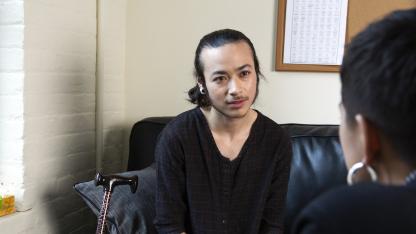 A genderqueer person sitting on the couch of a therapist