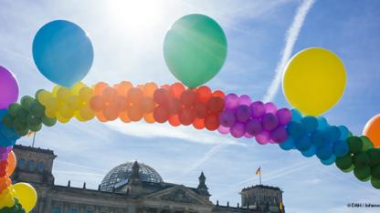 Eine Kette aus Luftballons in den Farben des Regenbogens vor dem Reichstagsgebäude